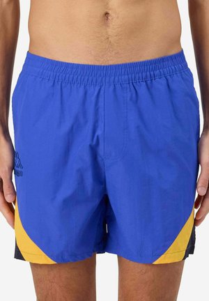Pantaloni da bagno blu con una cintura elastica, dettagli laterali gialli e rifiniture nere. Realizzati in materiale leggero e ad asciugatura rapida.