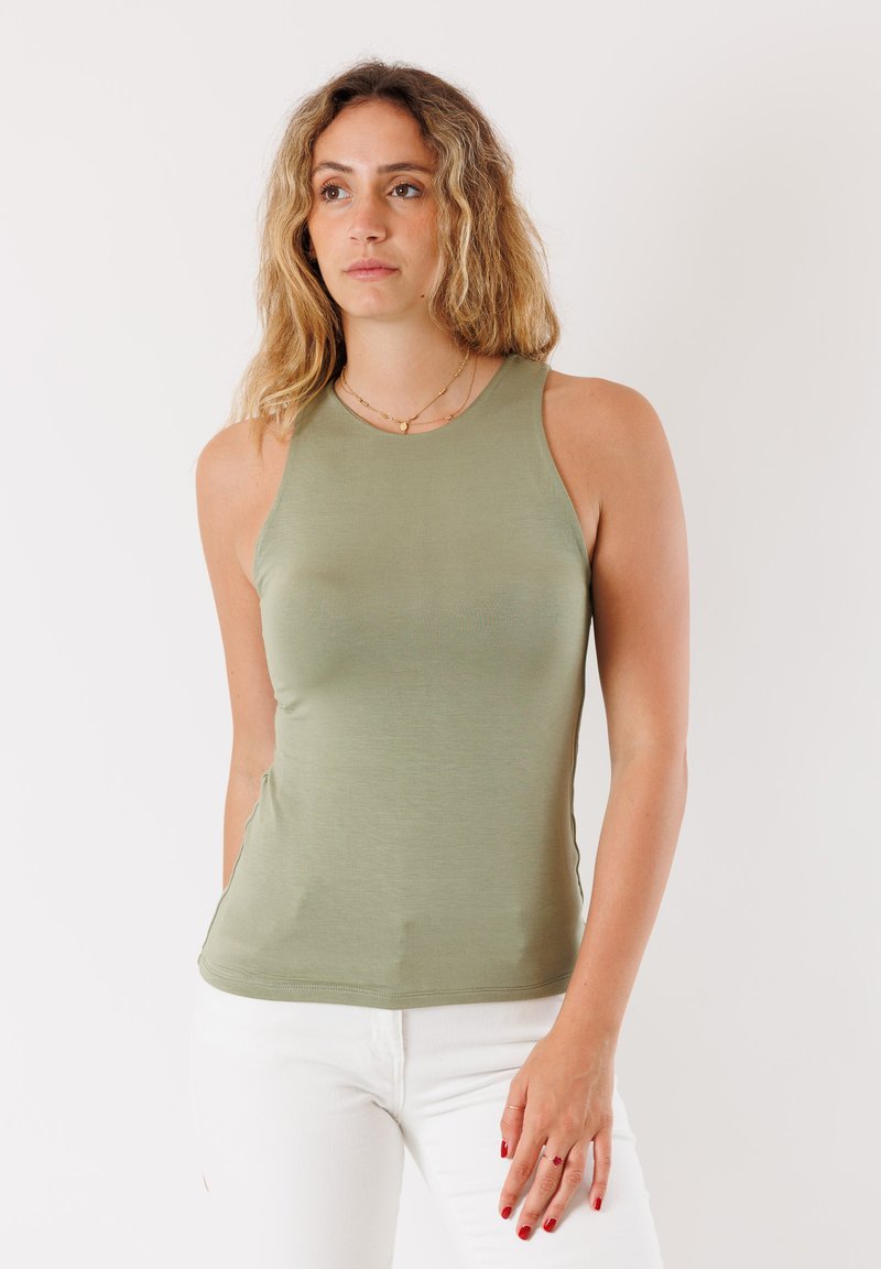 Top senza maniche verde oliva realizzato in tessuto liscio ed elastico con un design aderente. Presenta un colletto rotondo e spacco laterale per maggiore comfort.