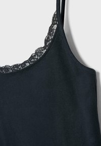 Černá košilka s tenkými ramínky a krajkovou ozdobou podél výstřihu na jednoduchém světlém pozadí.