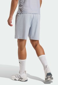 Light blue athletic shorts with side pockets, paired with white knee-high socks and white sneakers featuring grey accents.