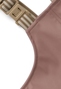 Accesoriu cu un material exterior moale, roz pal, cu o textură netedă; include o curea și o cataramă ajustabilă cu un model maroniu și bej.
