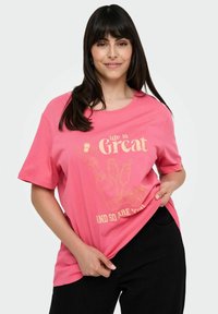 Różowa bawełniana koszulka z oversize'owym krojem, krótkimi rękawami i nadrukiem graficznym w złotym kolorze z napisem "życie jest wspaniałe, A TY TEŻ!".
