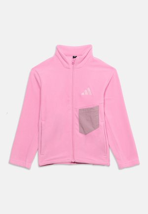 Värilt vaaleanpunainen fleece-takki, jossa koko pituinen vetoketju, pystykaulus, harmaa rintatasku ja vasemmassa rinnassa kirjailtu logo.