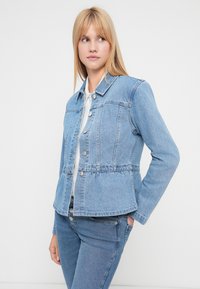 Ανοιχτό μπλε τζιν μπουφάν με εφαρμοστή μέση, κούμπωμα με κουμπιά μπροστά και κλασικό γιακά. Διαθέτει δύο τσέπες στο στήθος και ελαφρώς φαρδύ τελείωμα.