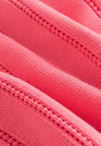 Korall rózsaszínű kötött anyag bordázott részekkel és finom csipke részletekkel. Sima tapintású, lágy, könnyű megjelenéssel.