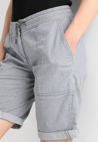 Szare spodenki w paski z elastycznym pasem, kieszeniami bocznymi i mankietami. Wykonane z teksturowanej tkaniny o swobodnym designie.