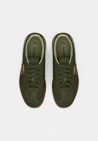 Tenisi verzi din suede cu talpă din cauciuc, având sireturi și amortizare Ortholite. Logo-uri pe limbă și pe lateral.