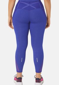 Leggings attivi viola con finitura testurizzata, vita alta, inserti in rete sui polpacci e dettagli riflettenti nella parte bassa delle gambe.