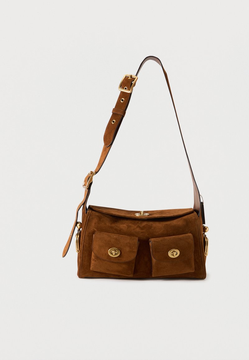 Καφέ τσάντα ώμου από σουέντ με ρυθμιζόμενο λουρί, δύο μπροστινές τσέπες με καπάκι και χρυσά κλείστρα περιστροφής, και επάνω καπάκι με αντίστοιχο κούμπωμα.