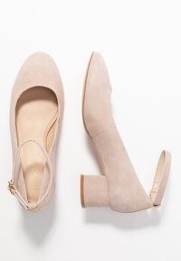 Scarpe beige in suede con tacco a blocco, punta rotonda e schiena aperta, dotate di un sottile cinturino alla caviglia e superficie liscia e testurizzata.