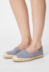 Espadryle w paski z płóciennym wierzchem w kolorze granatowym i białym, z jucianą podeszwą oraz skórzanym akcentem z detalem w postaci oznaczenia marki.