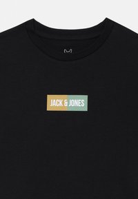 Čierne bavlnené tričko s klasickým okrúhlym výstrihom. Obsahuje obdĺžnikové logo v žltej a mentolovej farbe s nápisom "JACK & JONES" v bielej farbe.