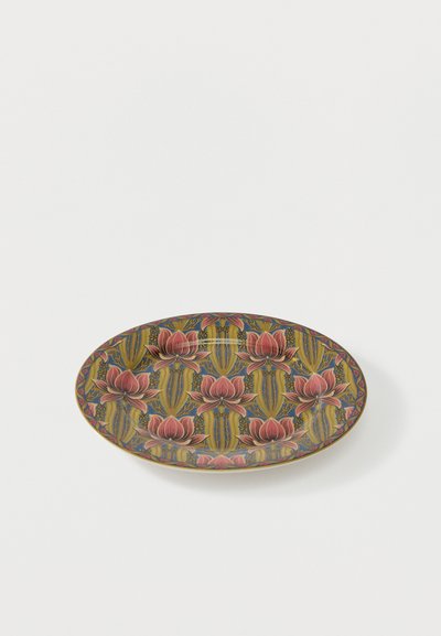 Assiette ovale en céramique avec un motif répétitif de lotus rose et de feuilles vertes sur un fond bleu et jaune.