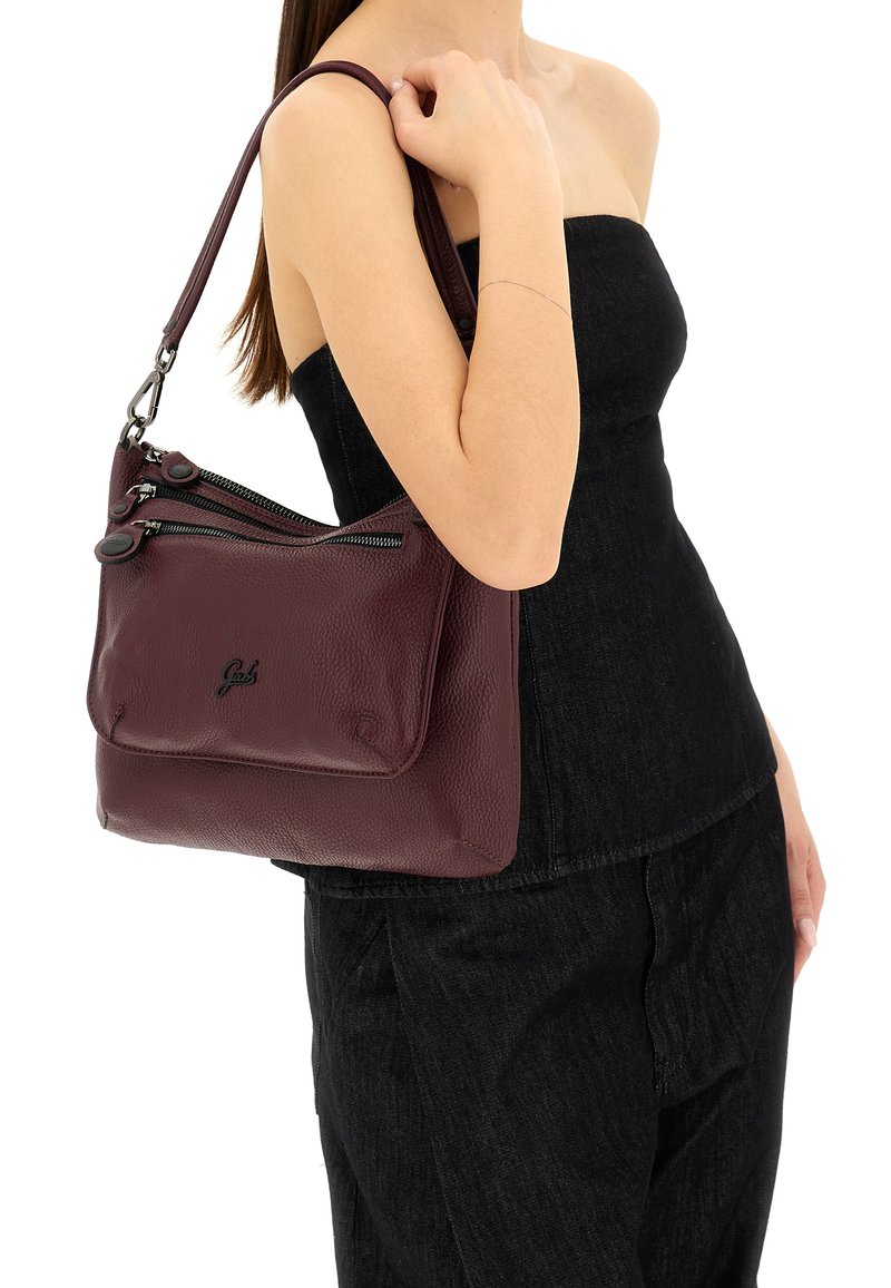 Borsa a spalla in pelle bordeaux con due scomparti con zipper, superficie texturizzata e tracolla rimovibile. Logo nero impresso sulla parte anteriore.