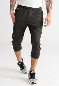 Pantalones cortos deportivos negros confeccionados en una tela suave y ligera, con un diseño ajustado y recortado, y un sutil logo de Nike en el muslo izquierdo.