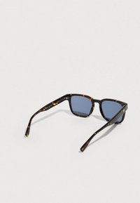 Tortoiseshell rectangular sunglasses with blue tinted lenses, folded and resting on a light gray surface.