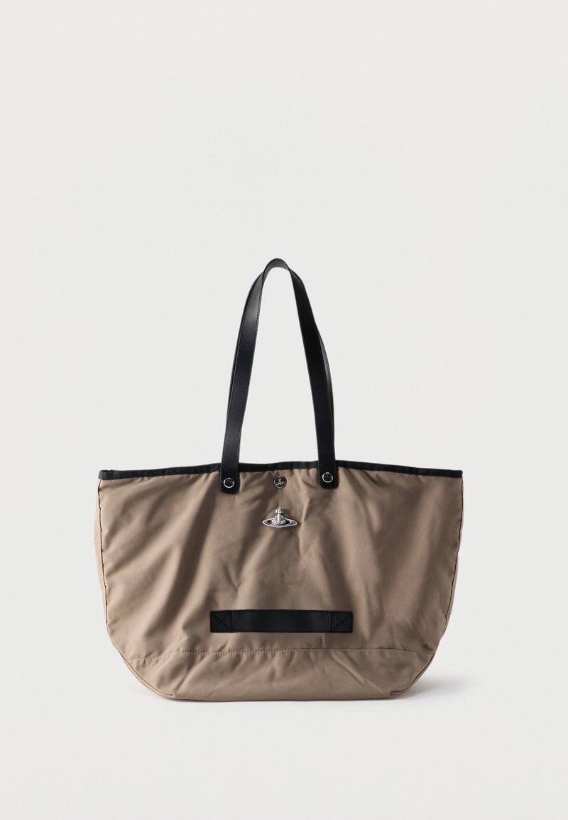 Bolso tote beige con asas negras, ribetes negros y cierre con logo plateado en el frente, descansando sobre un fondo blanco.