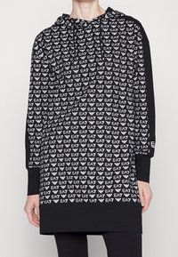Sudadera con capucha negra que presenta un patrón de logotipo EA7 en blanco en toda la prenda, mangas largas y un corte relajado. Fabricada con un tejido cómodo.