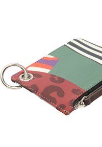 Kolorowy portfel z mieszanką wzorów, w tym zielonych, czerwonych i w paski. Z metalowym detalem w postaci pierścienia oraz zapięciem na zamek błyskawiczny. Teksturowane wykończenie.