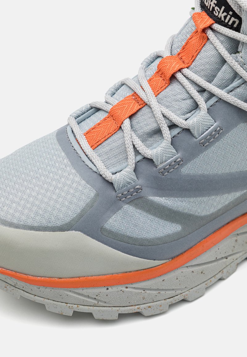 Hellblaue Sportschuhe mit strukturiertem Obermaterial, grauen Akzenten, orangefarbenen Schnürsenkeln und einer robusten Sohle mit gesprenkelten Details.