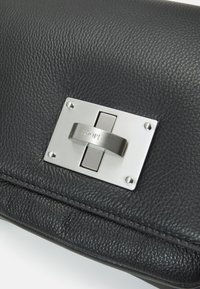 Black leather clutch bag featuring a textured surface, a silver metallic clasp with embossed logo, and visible stitching details.