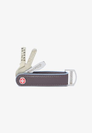 Portachiavi in pelle marrone con lame metalliche argentate e un emblema rosso con la croce svizzera. Presenta un design elegante e compatto con una clip integrata.