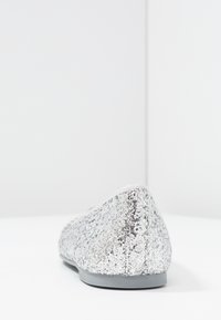 Ballerine di paillettes argento con punta arrotondata, superficie texturizzata e suola bassa in gomma grigia. Fodera morbida lungo il bordo superiore.
