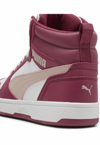 Kõrged tossud burgundi, valge ja beeži nahaga, millel on perforatsioonid, tekstuuriga aktsendid ja silmapaistev Puma logo külgmisel küljel.