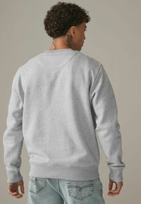 Grijs crewneck sweatshirt gemaakt van een katoenmix, met geribbelde mouwen en zoom. Van achter gezien heeft het een schone, eenvoudige uitstraling.