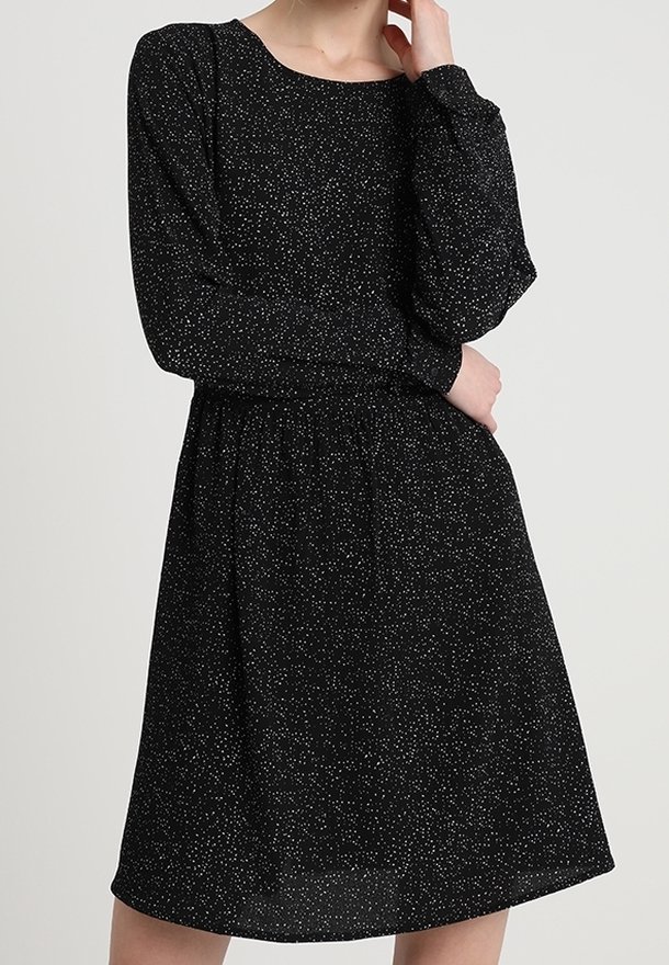 Robe noire à manches longues, avec un col rond et une taille élastique. Décorée d'un subtil motif moucheté blanc.
