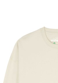 Sweatshirt beige clair à manches longues avec un col rond, fabriqué en tissu doux. Présente des coutures visibles et une petite étiquette au niveau du cou.