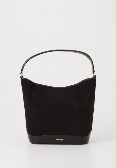Bolso de hombro de ante negro con una base de cuero negro liso. Cuenta con un asa redondeada y un logo dorado "SANDRO" en la parte frontal.