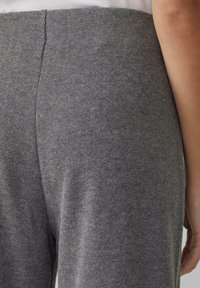 Grau gerippter Stoff mit einer glatten Textur, ausgestattet mit einem schmalen Bund und einem weichen, taillierten Bein-Design. Keine sichtbaren Muster oder Beschläge.
