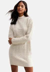 Cremfarbendes, kabelstrick gestricktes Kleid mit hohem Kragen und gerippten Bündchen. Merkmale ein strukturiertes Muster und ein figurbetontes Design, das oberhalb des Knies endet.