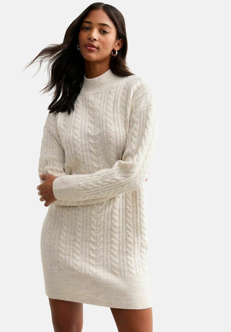 Cremfarbendes, kabelstrick gestricktes Kleid mit hohem Kragen und gerippten Bündchen. Merkmale ein strukturiertes Muster und ein figurbetontes Design, das oberhalb des Knies endet.