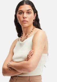 Lys beige ribbet tanktop med tynde spaghetti-stropper, parret med en chunky sølv kæde-n Halskæde og hoop øreringe.