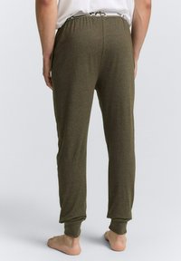 Olijfgroene katoenen joggers met een elastische tailleband en boorden, met een gladde textuur en een minimaal ontwerp, van achter bekeken.