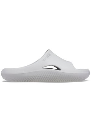 Hvid slip-on sandal med struktureret sål og ventilationshul i siden, med et hævet logo på den øvre rem.