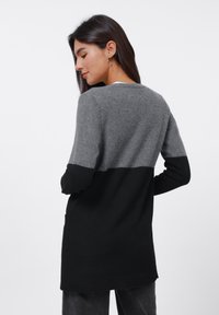 Long sweater in gray and black wool blend, featuring color-block design, ribbed hem, and long sleeves. Smooth texture with a relaxed fit.