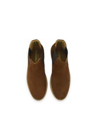 Chaussures en daim marron à enfiler avec des panneaux élastiques sur les côtés, des coutures beiges le long de la semelle et une texture lisse. Pas de motifs ni d'ornements visibles.