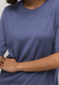 Kortærmet crewneck sweater i blødt, tekstureret lysblåt stof. Har en afslappet pasform med ribbet manchetter og krave.