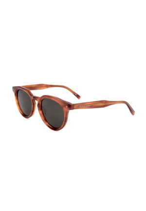 Occhiali da sole rotondi in tartaruga marrone con lenti scure e aste sottili, con un discreto logo del marchio sulla stanghetta.