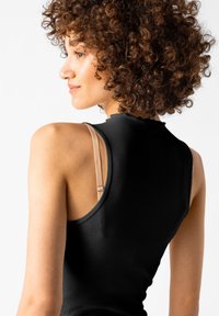 Czarny prążkowany top bez rękawów z wysokim dekoltem. Wyróżnia się widocznym cielistym ramiączkiem od biustonosza na jasnym tle.