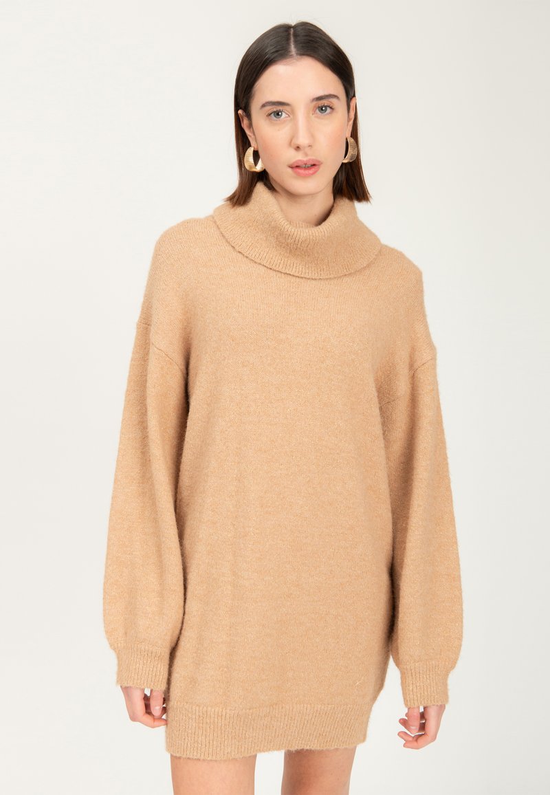 Beige strik turtleneck sweater med dropped shoulders og lange ærmer. Blød tekstur og ribbede manchetter samt kant. Midt på låret længde.
