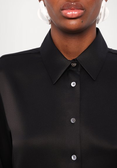 Chemise noire à col en tissu lisse avec un devant à boutons. Présente des boutons transparents et des bords de col nets. Design simple.