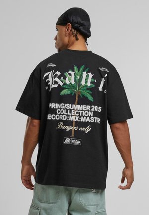 Schwarzes Baumwoll-T-Shirt mit einem großen Grafikdesign eines Palmenbaums und Text auf dem Rücken. Lockere Passform, kurze Ärmel und Rundhalsausschnitt.