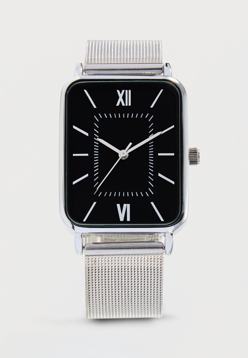 Montre-bracelet rectangulaire en argent avec cadran noir, chiffres romains blancs, marqueurs des minutes, et bracelet en maille argentée affichant l'heure 10:10:37.