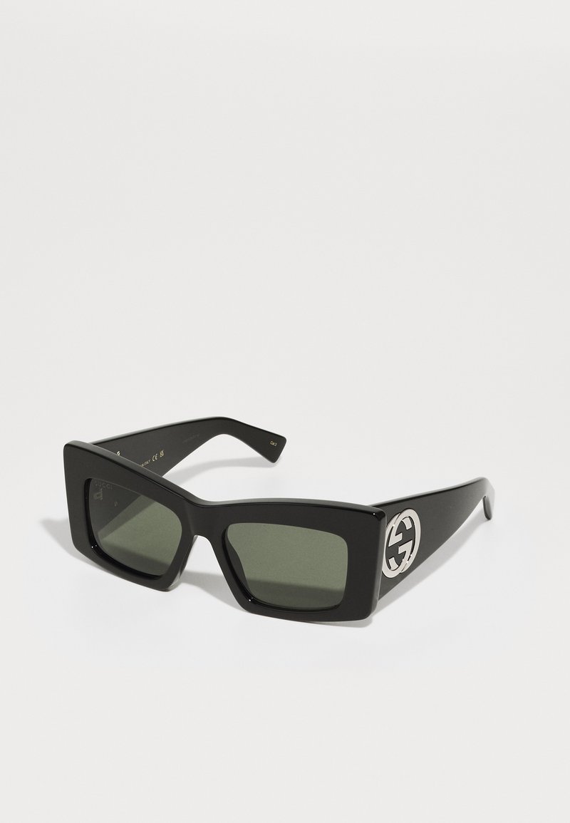 Black square sunglasses with dark green lenses. Features a silver GG logo on the side. Made of glossy plastic with thick frames.