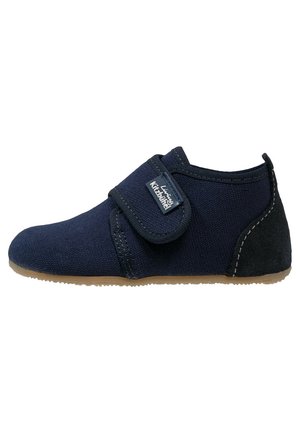 Chaussure bébé en tissu doux bleu marine avec semelle marron, bride ajustable à scratch et patch talon en daim noir.