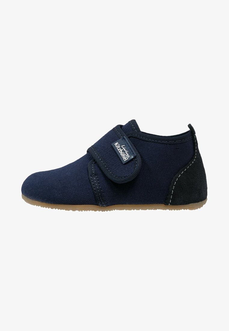 Chaussure bébé en tissu doux bleu marine avec semelle marron, bride ajustable à scratch et patch talon en daim noir.